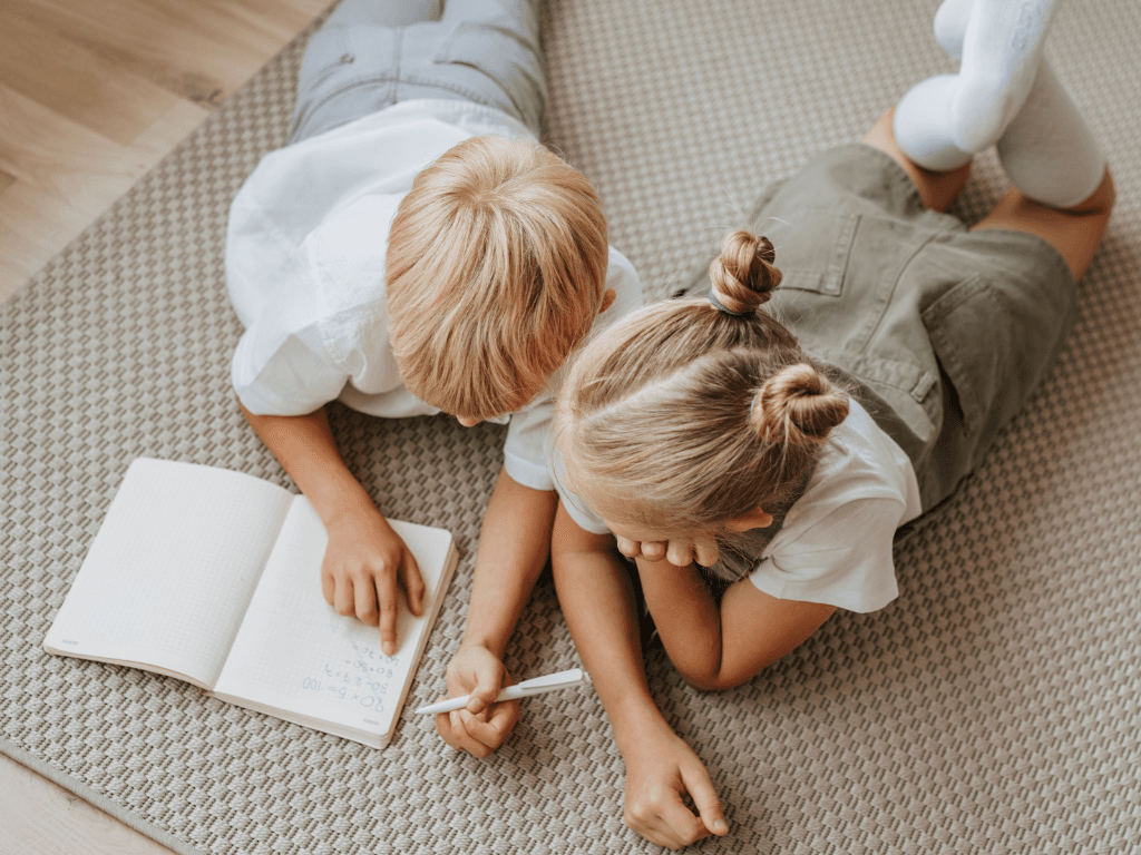 Image représentant deux enfants en train de lire et d'écrire sur un livre